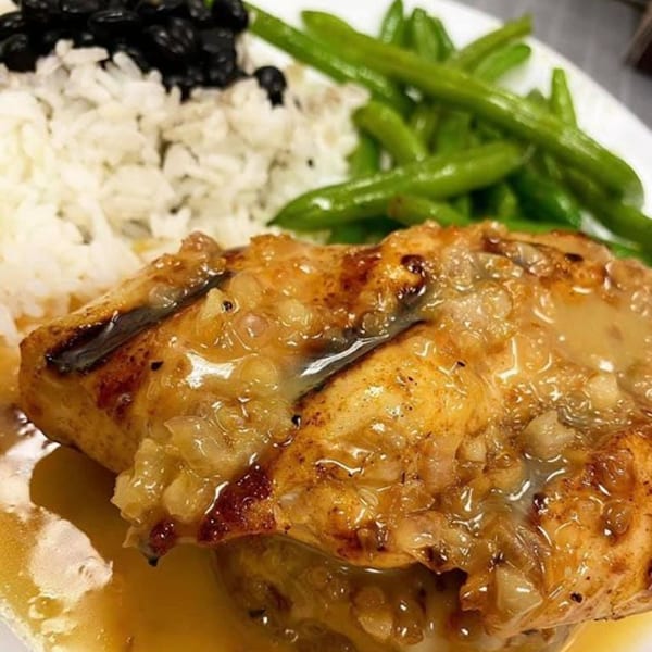 Grilled fish with a savory sauce, served with white rice, black beans, and green beans.