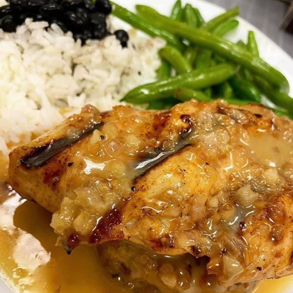 Grilled fish with a savory sauce, served with white rice, black beans, and green beans.